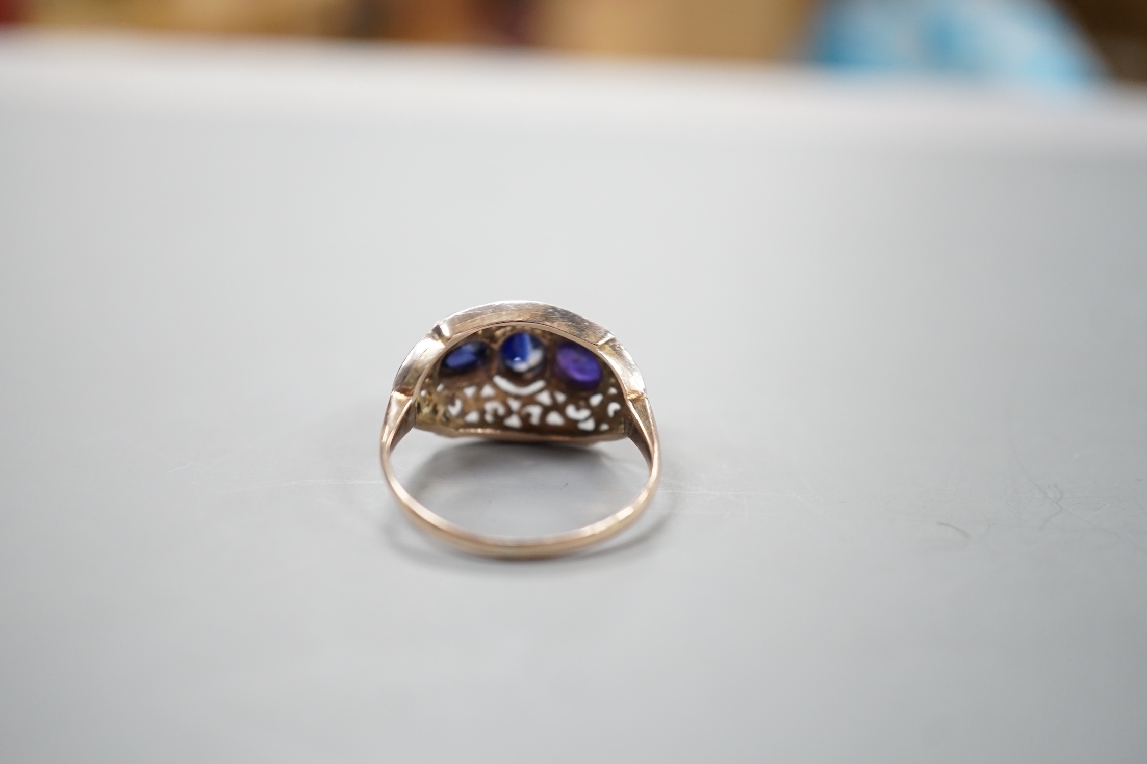 A pierced yellow and white metal, three stone gem set dress ring, size IO/P, gross weight 4.1 grams.